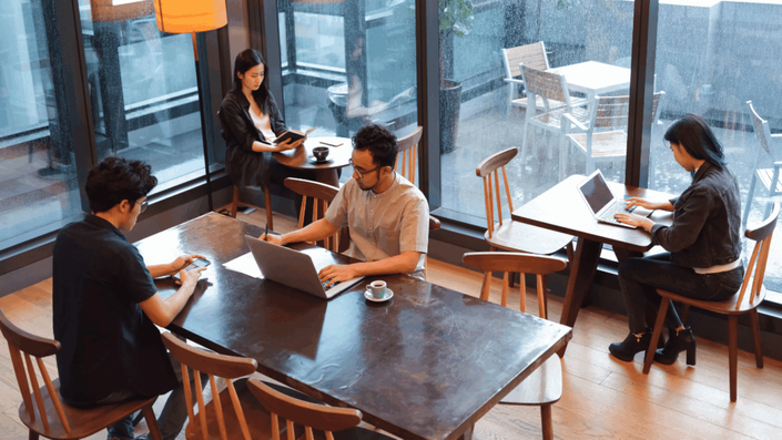 Two professionals collaborate in a modern co-working space, using a laptop to network and create content for LinkedIn, reflecting current B2B Social Media Trends.