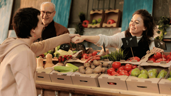 A customer and a vendor interacting at a traditional outdoor food market, highlighting personal connections and quality in the French market.