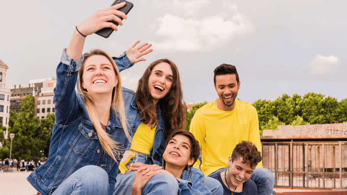 A diverse group of young friends laugh together while creating a video for TikTok, embracing current Social Media Trends in content creation.