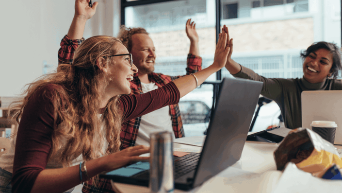 An energetic and diverse startup team celebrating a small victory in their office, highlighting the power of internal networking and teamwork.