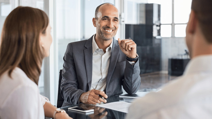 A financial advisor discussing ESG investment reports with clients in an office, highlighting the importance of responsible investing.