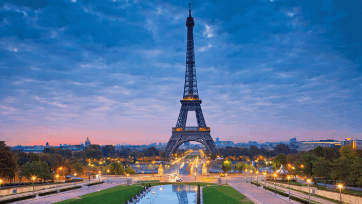 The iconic Eiffel Tower illuminated with golden lights against a twilight sky, representing the stability and prestige of investing in France.