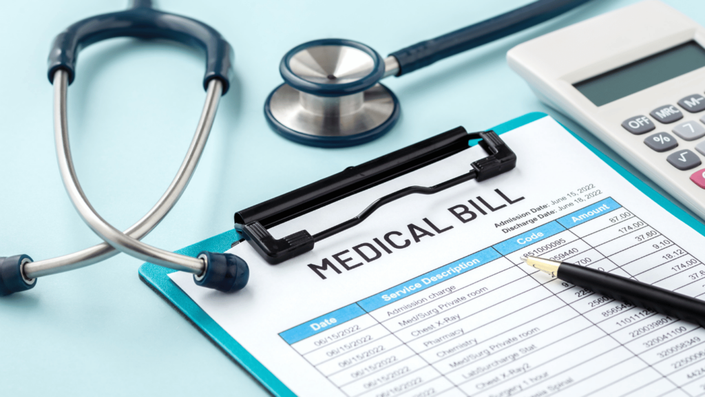 A close-up of a medical bill, calculator, and stethoscope on a blue background, emphasizing the importance of emergency funds for unexpected healthcare expenses.