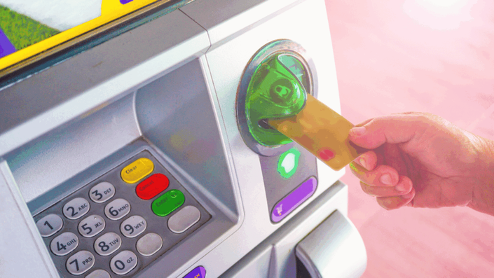 A person uses an ATM at a traditional bank branch, representing the physical accessibility and services offered in the traditional Banking landscape.