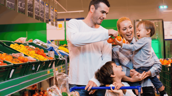 A family of four shopping for fresh produce in a French supermarket, illustrating the Cost of Living for families in France in 2025.