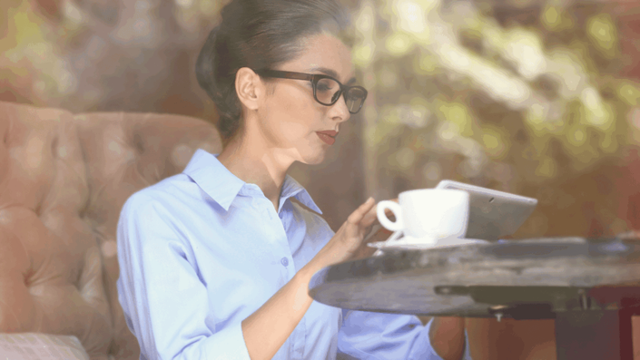 A stylishly dressed professional working on a tablet inside a classic Parisian café, representing digital adoption and business culture in the French market.